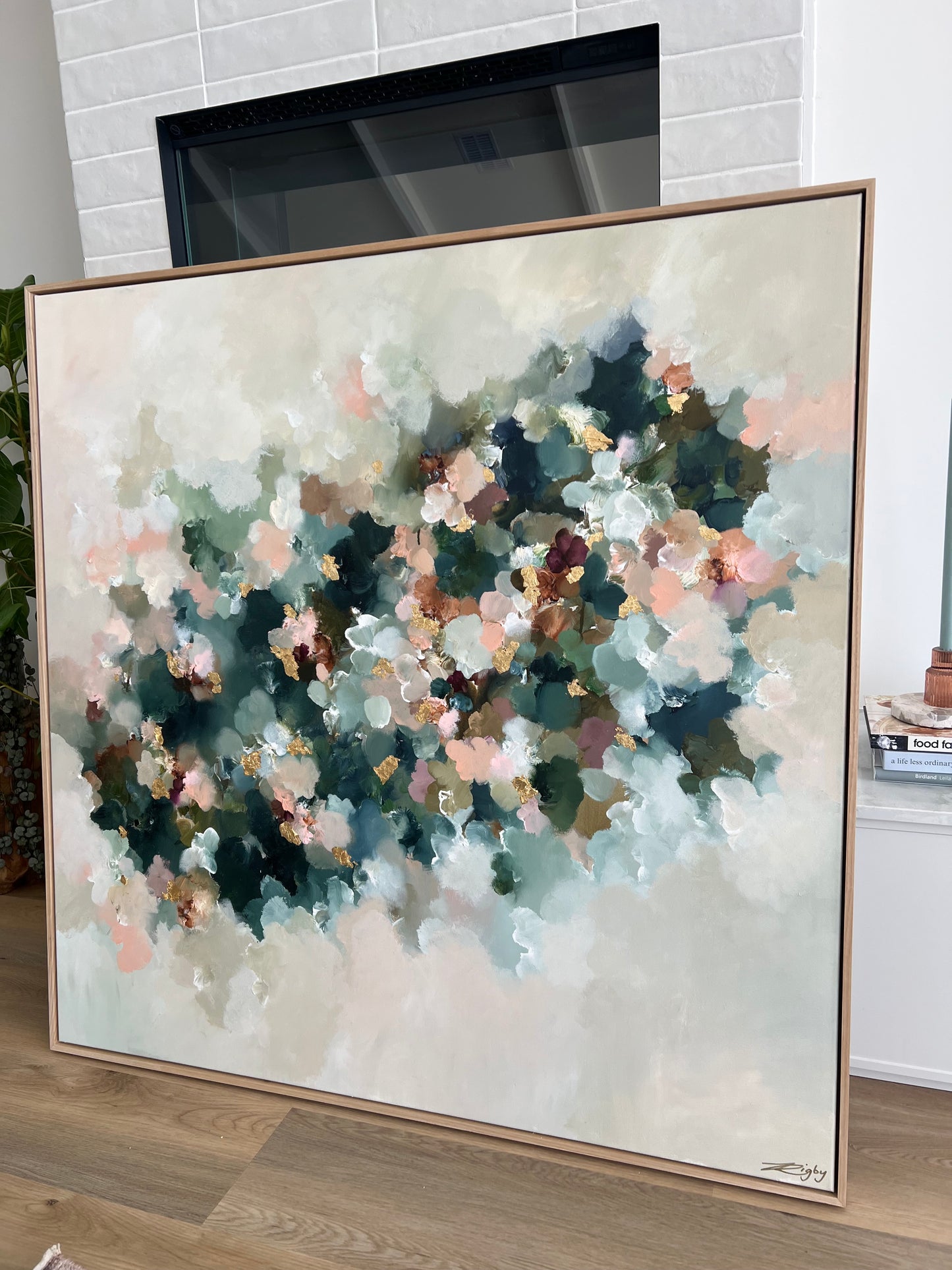 Framed abstract painting with soft colors on a wall.