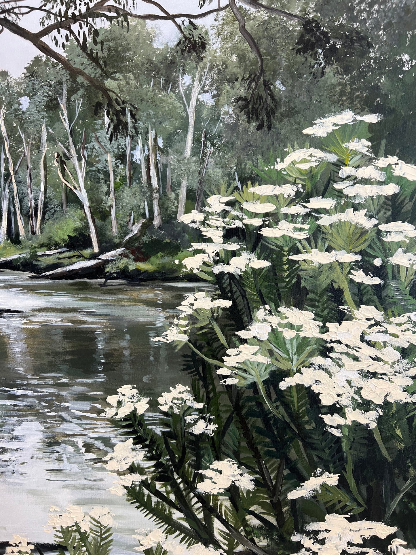 The Yarra, A landscape painting depicting a river flowing past a dense cluster of white flowers in the foreground, with a forest of tall, slender trees in the background.