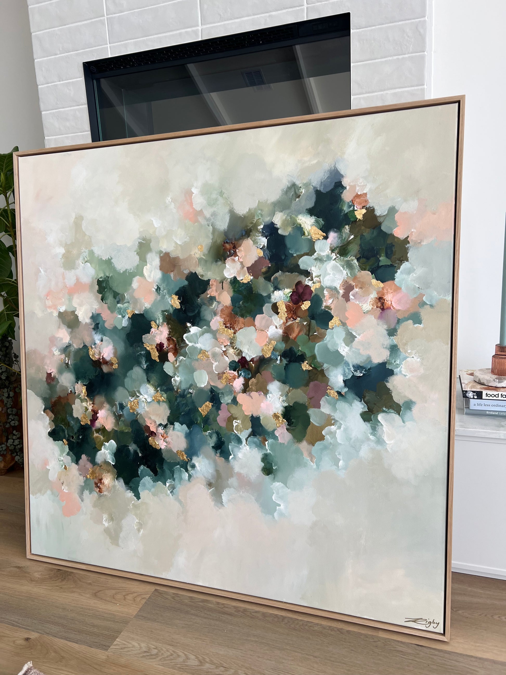 Framed abstract painting with soft colors on a wall.