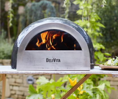 Delivita outdoor pizza oven with flames inside on a table outdoors.