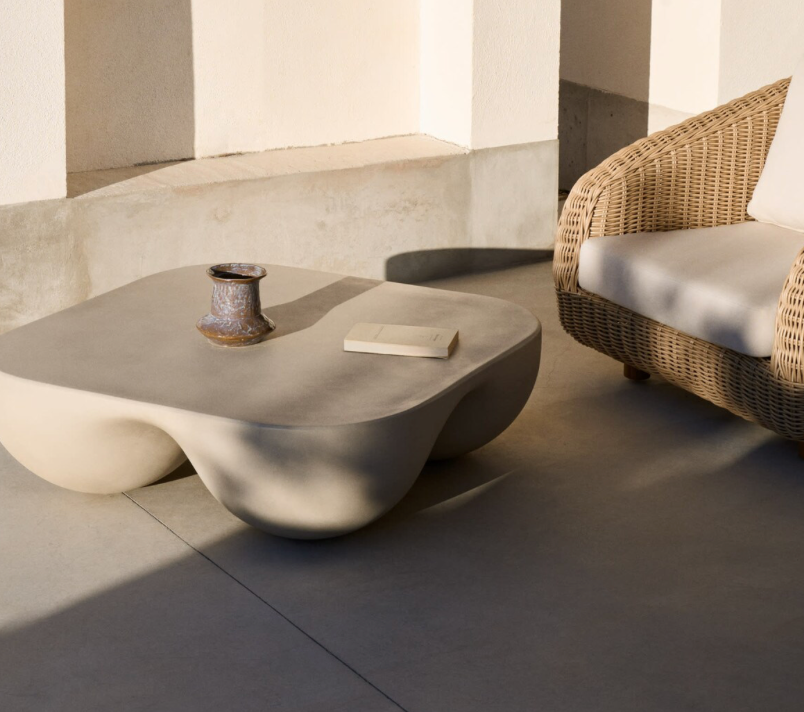 Modern outdoor setting with a wicker chair and concrete coffee table.
